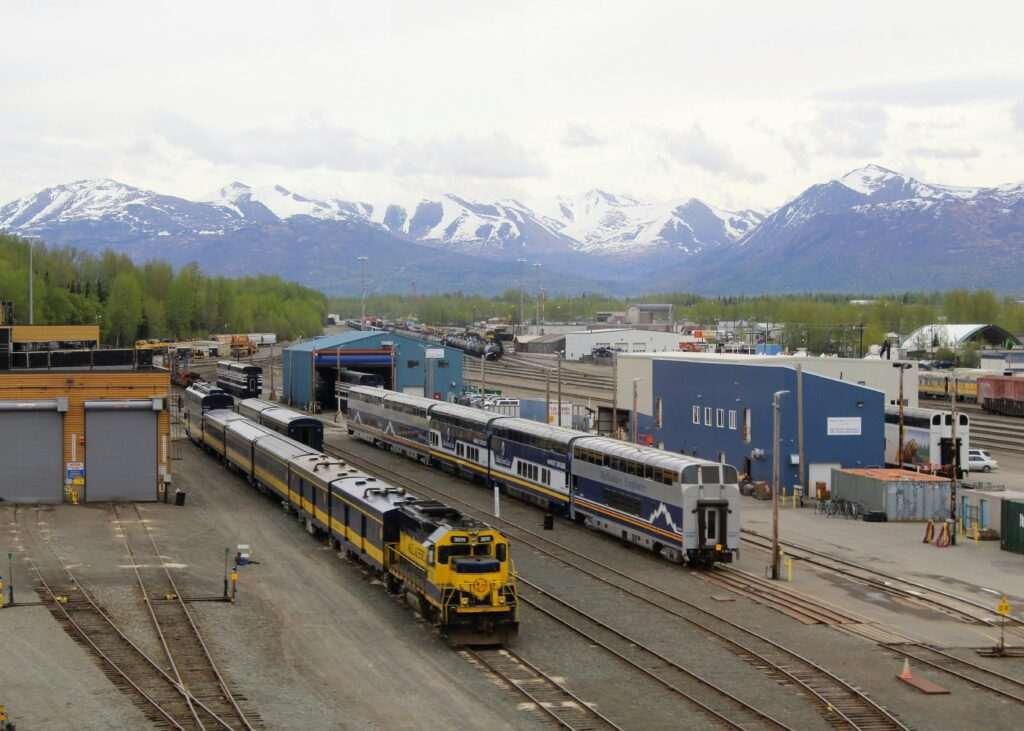 Anchorage train yard with snow-capped mountains and parked trains in Alaska