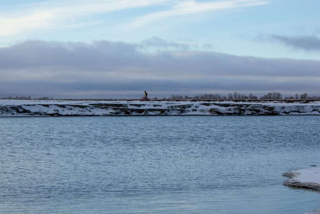 Cyclist riding along a snowy winter trail for a fat tire biking guide to Anchorage